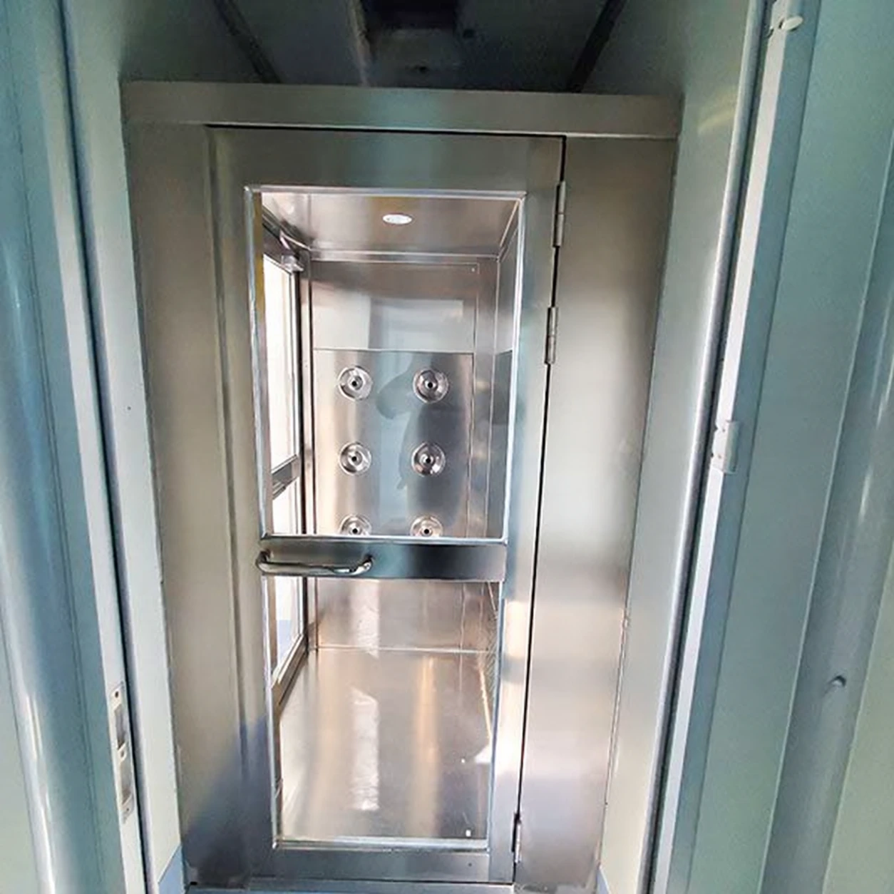 Stainless air shower fitted into a partitioned room entrance