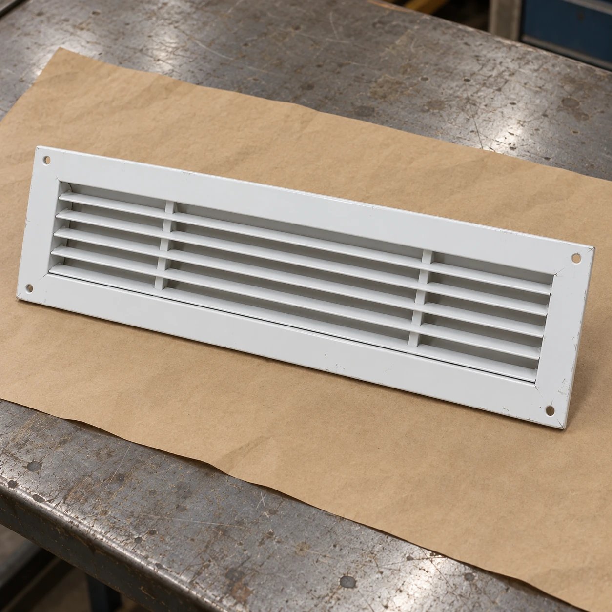 Shallow fourteen-by-six white return grille on a workshop packing surface
