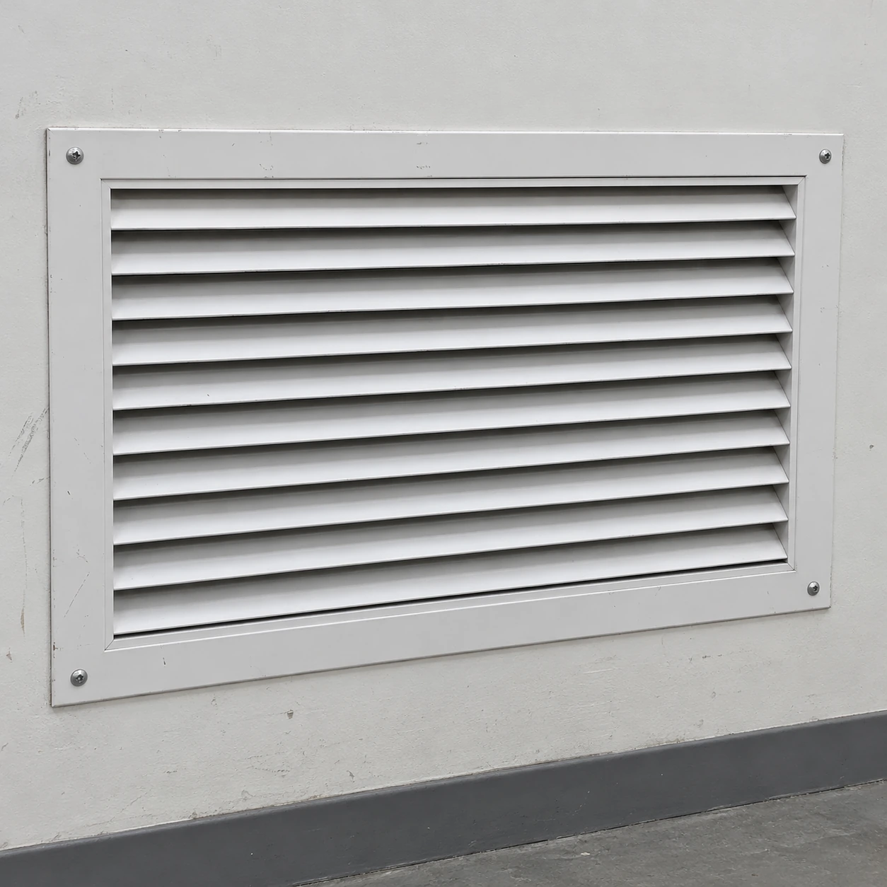 White horizontal-blade return grille mounted in a plain industrial wall section